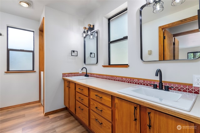 bathroom with wood-type flooring, vanity, a notable chandelier, and a healthy amount of sunlight