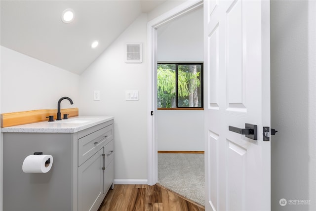 bathroom featuring vanity, hardwood / wood-style floors, and vaulted ceiling