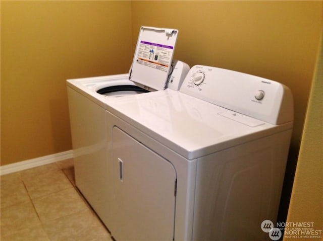 laundry room with laundry area, washing machine and dryer, light tile patterned floors, and baseboards