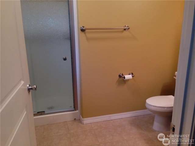 bathroom featuring baseboards, a shower stall, toilet, and tile patterned floors