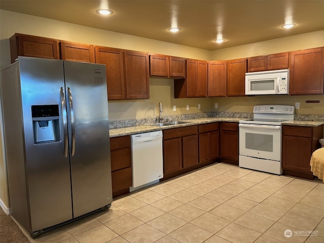 kitchen with light stone counters, light tile patterned flooring, recessed lighting, white appliances, and a sink