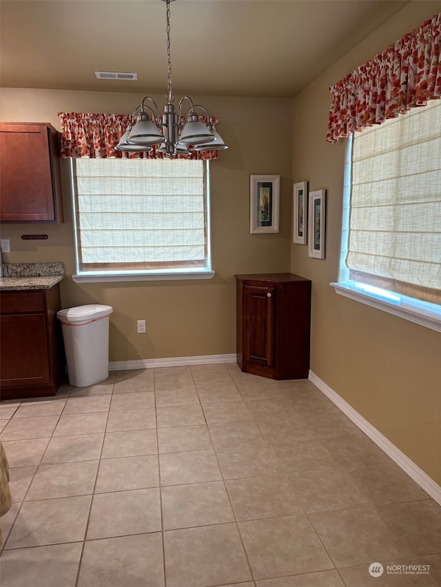 unfurnished dining area with a chandelier, light tile patterned floors, visible vents, and baseboards