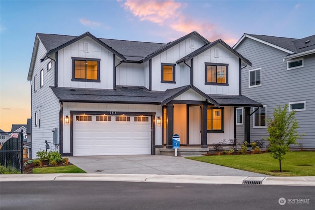 modern inspired farmhouse with a shingled roof, concrete driveway, an attached garage, a front lawn, and board and batten siding