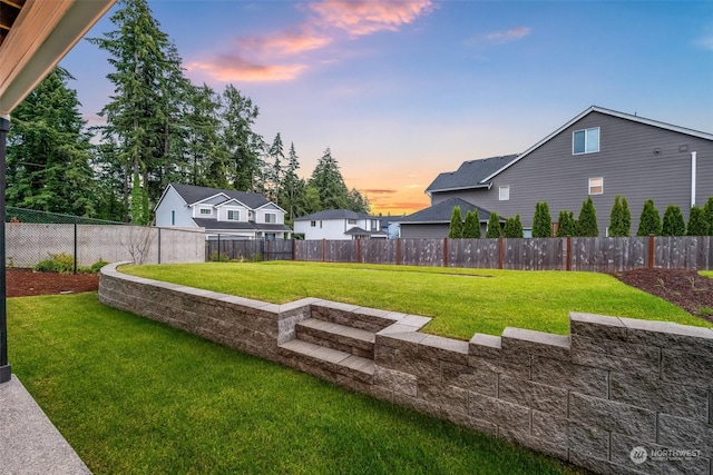 yard at dusk featuring a fenced backyard