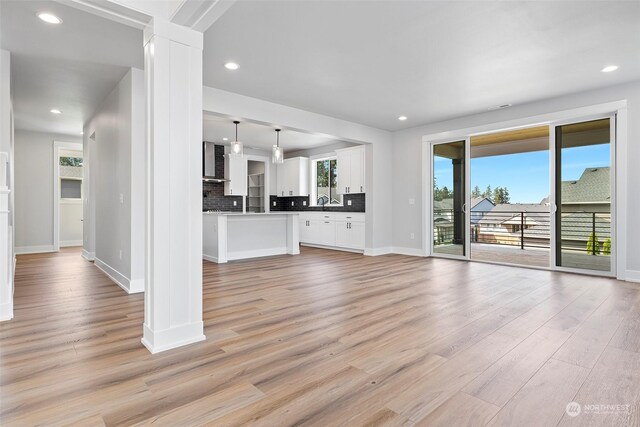 unfurnished living room with light wood-type flooring and ornate columns