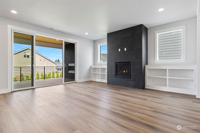 unfurnished living room with light hardwood / wood-style floors and a tile fireplace