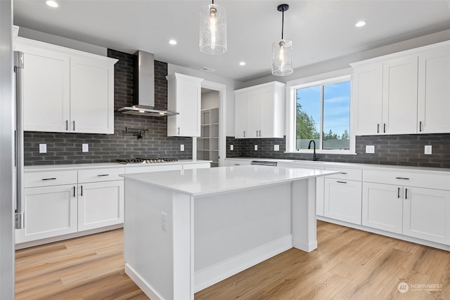 kitchen with wall chimney exhaust hood, decorative backsplash, light hardwood / wood-style flooring, and white cabinets