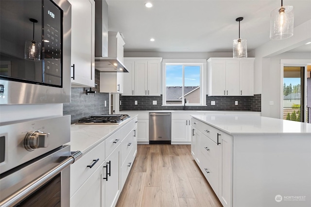 kitchen with wall chimney exhaust hood, appliances with stainless steel finishes, and white cabinets