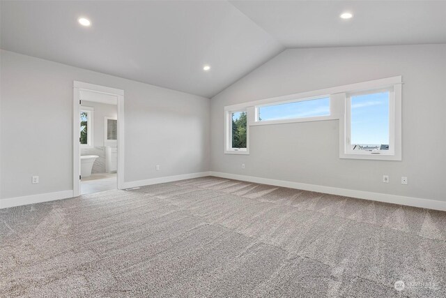 carpeted empty room with lofted ceiling