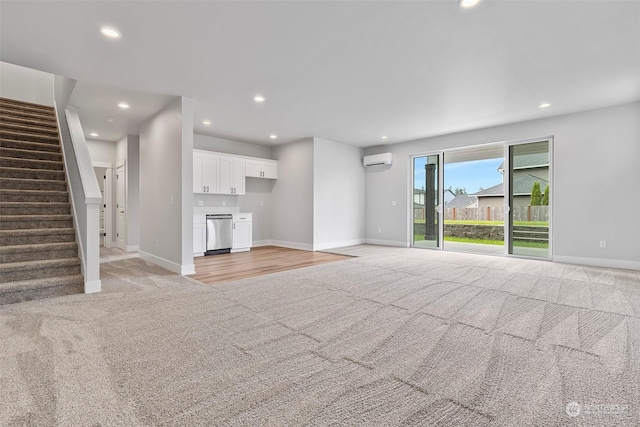 unfurnished living room featuring stairway, a wall mounted air conditioner, light carpet, and baseboards