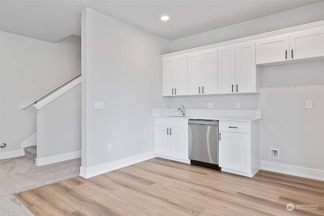 kitchen featuring sink, white cabinetry, stainless steel dishwasher, and light carpet