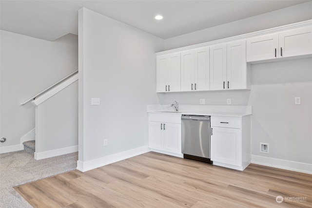 kitchen with dishwasher, light countertops, white cabinetry, and baseboards