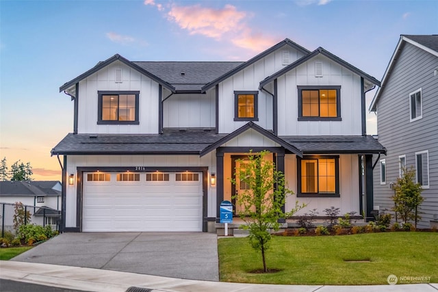 modern farmhouse style home featuring a garage, a shingled roof, concrete driveway, a front lawn, and board and batten siding