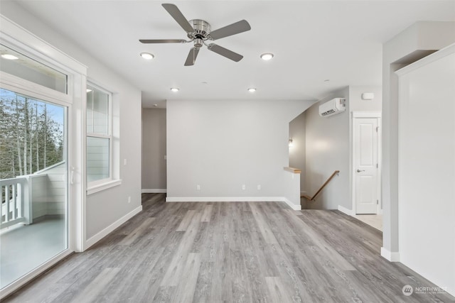 spare room featuring ceiling fan, light wood-type flooring, and a wall unit AC