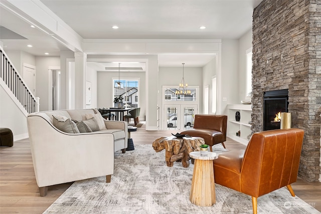 living room with a fireplace, an inviting chandelier, and light wood-type flooring