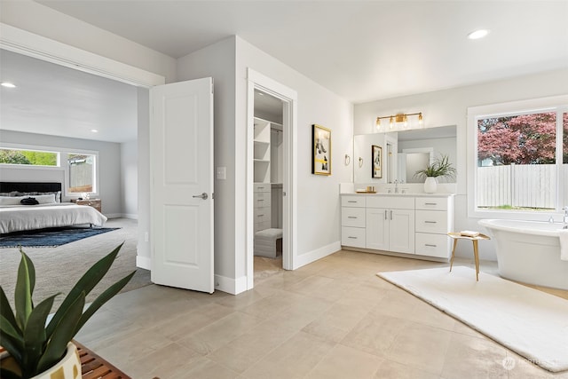 bathroom with a washtub, vanity, and tile patterned floors