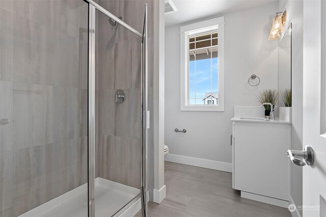 bathroom featuring toilet, walk in shower, and vanity