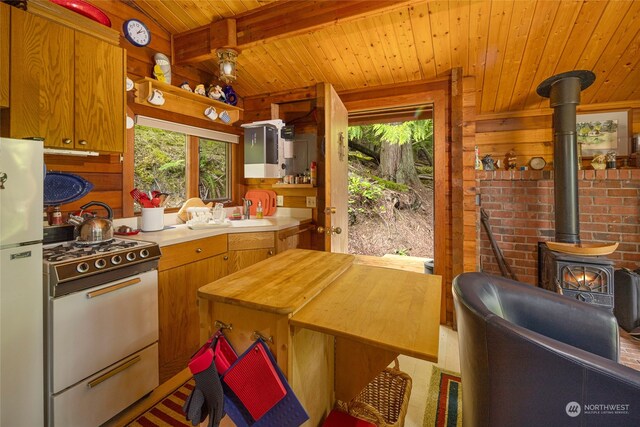 kitchen with wooden ceiling, white appliances, a wood stove, and beamed ceiling