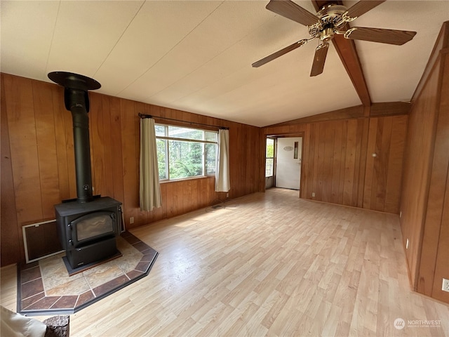 1411 300th Pl, Ocean Park, WA 98640 - unfurnished living room featuring a wood stove, wood walls, light hardwood / wood-style floors, and lofted ceiling with beams