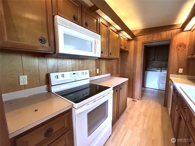 1411 300th Pl, Ocean Park, WA 98640 - kitchen featuring wood walls, washing machine and dryer, sink, light hardwood / wood-style flooring, and white appliances