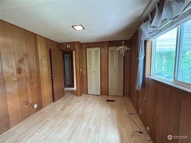 1411 300th Pl, Ocean Park, WA 98640 - unfurnished bedroom with wood walls, light hardwood / wood-style floors, and two closets