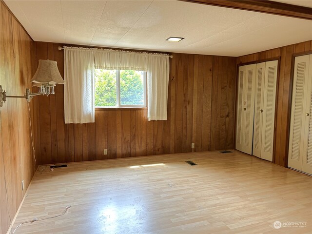 1411 300th Pl, Ocean Park, WA 98640 - unfurnished bedroom featuring multiple closets, light hardwood / wood-style flooring, and wood walls