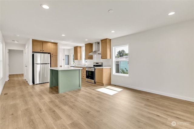 kitchen with wall chimney exhaust hood, a center island, light hardwood / wood-style floors, and stainless steel appliances