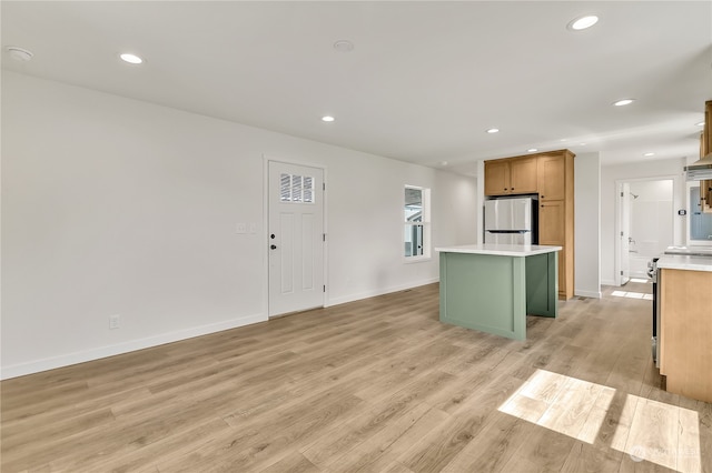 kitchen with stainless steel refrigerator, light hardwood / wood-style floors, and a kitchen island