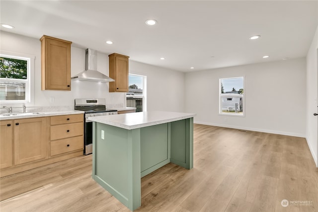 kitchen with a kitchen island, wall chimney exhaust hood, stainless steel electric range, plenty of natural light, and light hardwood / wood-style floors