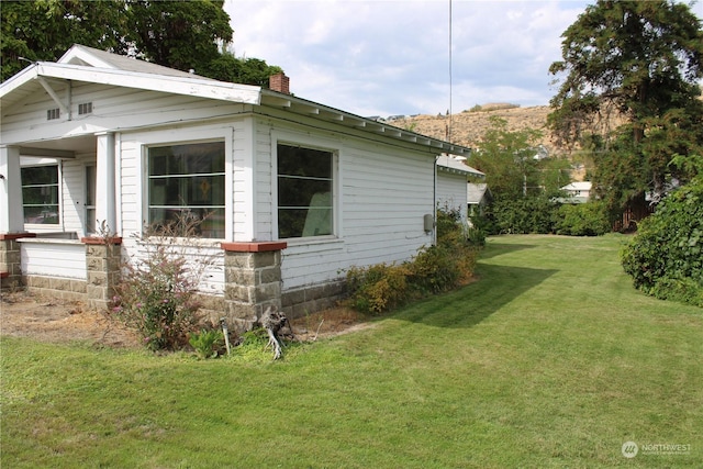 view of home's exterior featuring a chimney and a yard