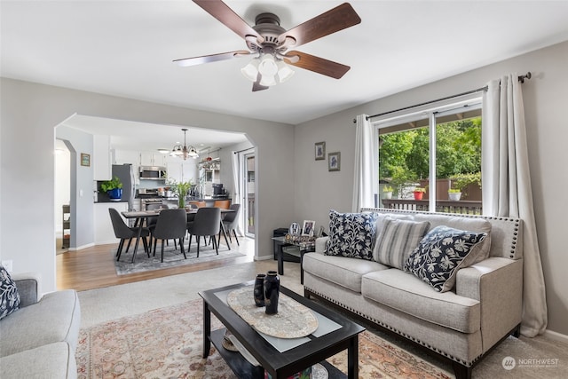 living room with ceiling fan with notable chandelier and hardwood / wood-style floors