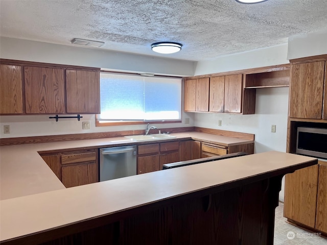 kitchen with appliances with stainless steel finishes, light tile patterned floors, sink, kitchen peninsula, and a textured ceiling