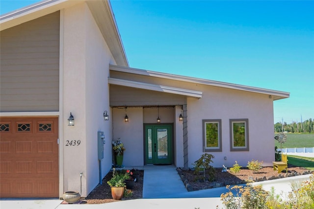 doorway to property with stucco siding, french doors, and a garage