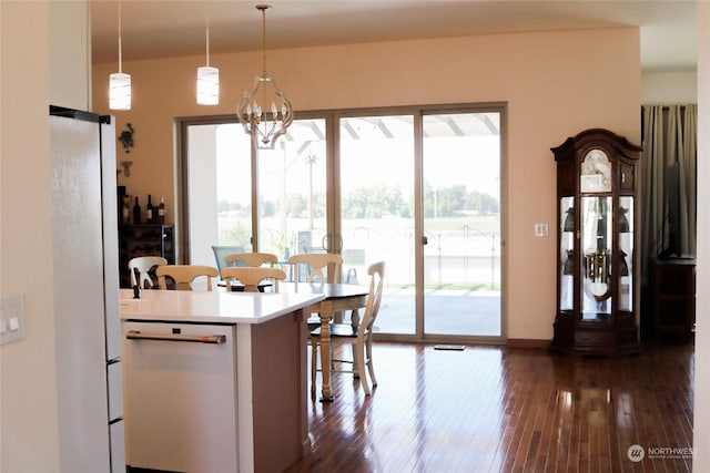 kitchen with pendant lighting, light countertops, freestanding refrigerator, dark wood-style floors, and a notable chandelier