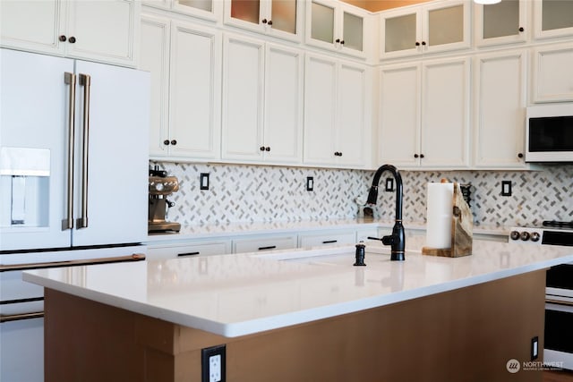 kitchen featuring a sink, white appliances, white cabinetry, and light countertops