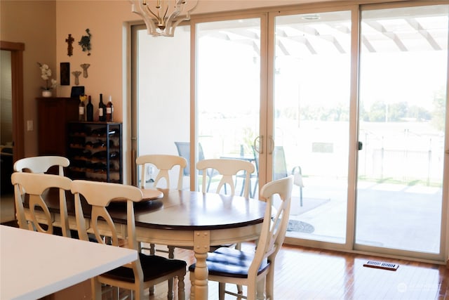 dining space with a chandelier, a wealth of natural light, french doors, and wood-type flooring