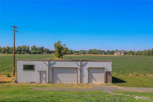 garage with a rural view and a yard