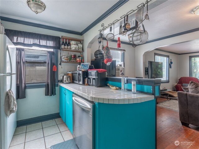 kitchen with dishwasher, ornamental molding, refrigerator, light wood-type flooring, and tile countertops