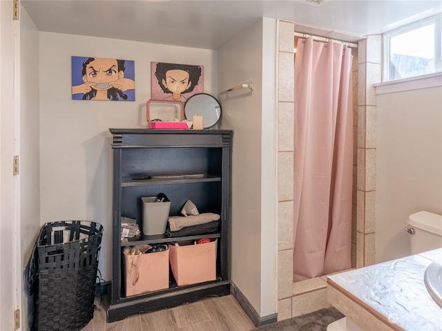 bathroom with hardwood / wood-style floors, toilet, and walk in shower