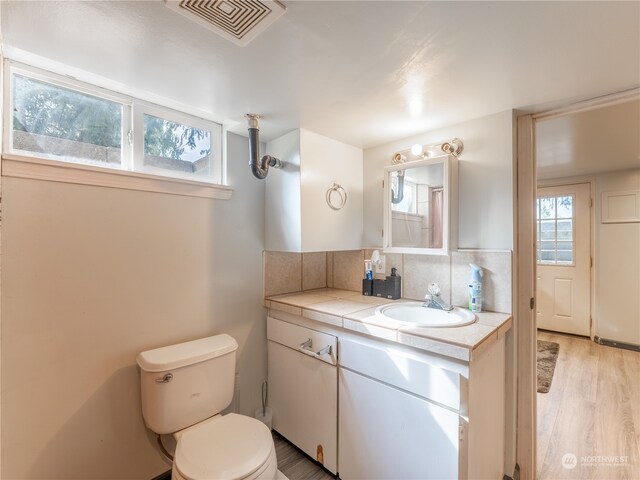 bathroom with decorative backsplash, toilet, hardwood / wood-style floors, and vanity