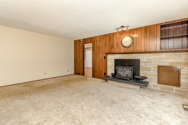 17407 36th Ave E, Tacoma, WA 98446 - unfurnished living room with wooden walls, a wood stove, carpet, and a textured ceiling