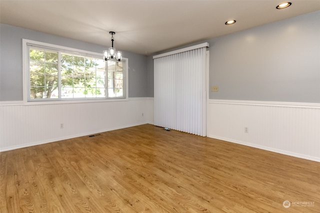 unfurnished room with hardwood / wood-style flooring and a notable chandelier