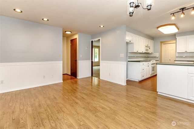 17407 36th Ave E, Tacoma, WA 98446 - kitchen with a wainscoted wall, dark countertops, white cabinetry, light wood-style floors, and white microwave