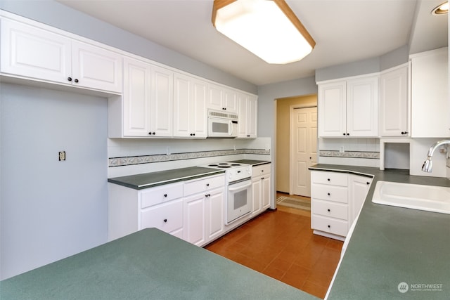 kitchen with white appliances, backsplash, white cabinetry, and sink