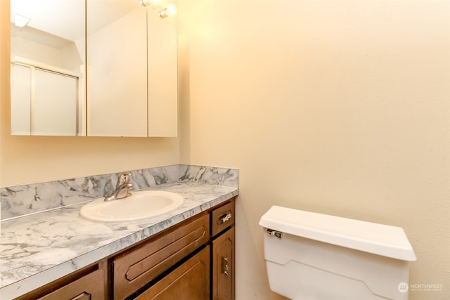 bathroom featuring walk in shower, toilet, and vanity