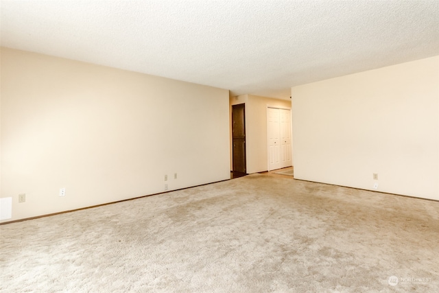 spare room with a textured ceiling and light carpet