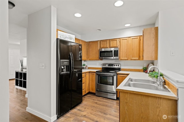 kitchen featuring light countertops, appliances with stainless steel finishes, a sink, and light wood-style flooring