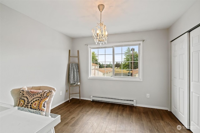 interior space with a baseboard heating unit, a notable chandelier, wood finished floors, and baseboards