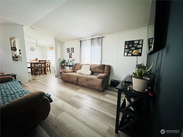 living room with light hardwood / wood-style flooring, vaulted ceiling, and crown molding