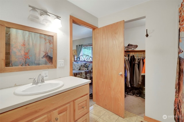 bathroom featuring a walk in closet, connected bathroom, vanity, and tile patterned floors